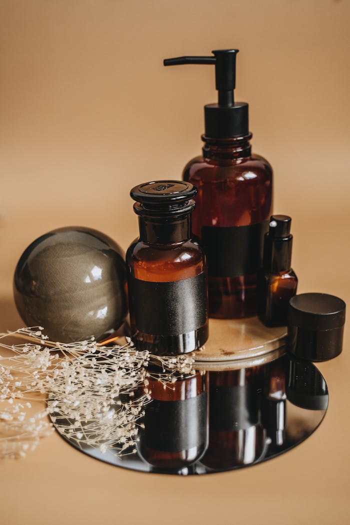 Sophisticated display of amber bottles and delicate flowers on a reflective surface, ideal for product branding.